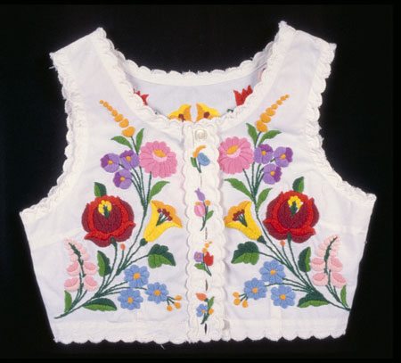 Gilet sans manches en coton blanc, orné d'un motif floral brodé multicolore. Il possède 5 boutons et une bordure à zigzags., © MCC/CMC, 76-514.2