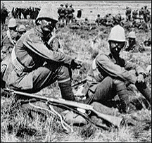 A group of soldiers sitting on the ground with rifles.