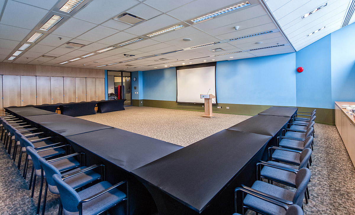 Une salle de conférence avec chaises et écran de projection, située à Ottawa au Musée canadien de la guerre.