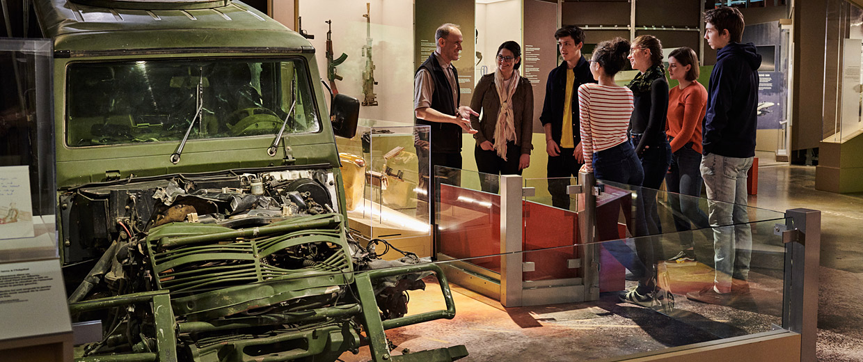 Des visiteurs examinant un vieux camion au Musée canadien de la guerre à Ottawa.