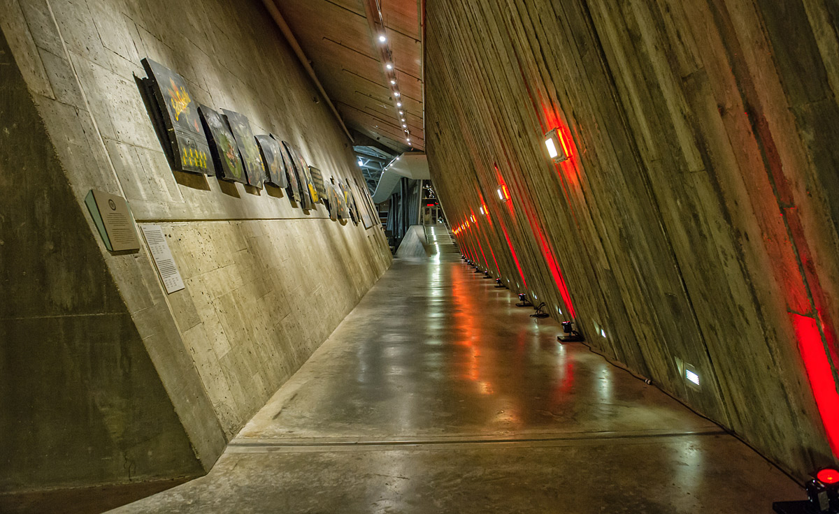 Le Musée canadien de la guerre à Ottawa présente un couloir orné de peintures remarquables aux murs, éclairé par des lumières rouges captivantes.