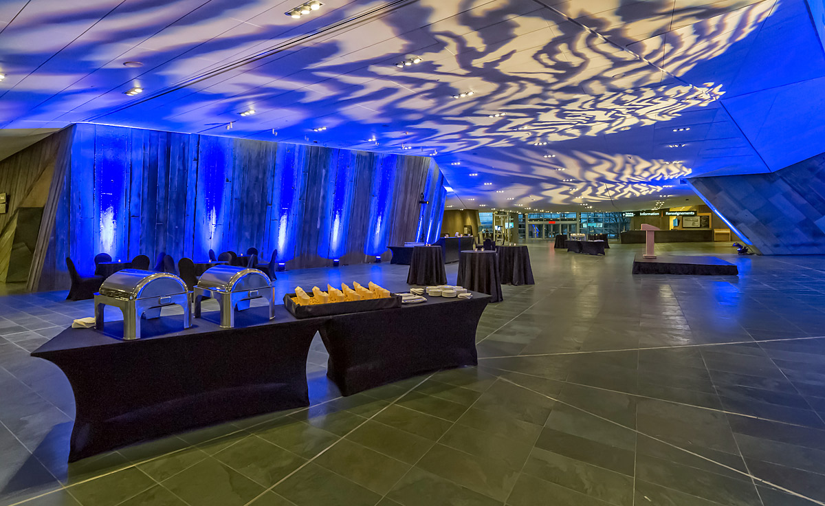 Une grande salle avec un éclairage bleu et des tables au Musée canadien de la guerre.