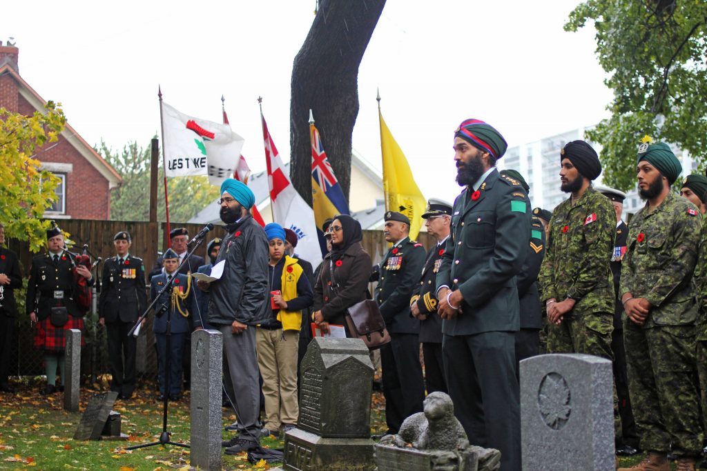 Un groupe de personnes debout devant une tombe avec des drapeaux au Musée canadien de la guerre à Ottawa.