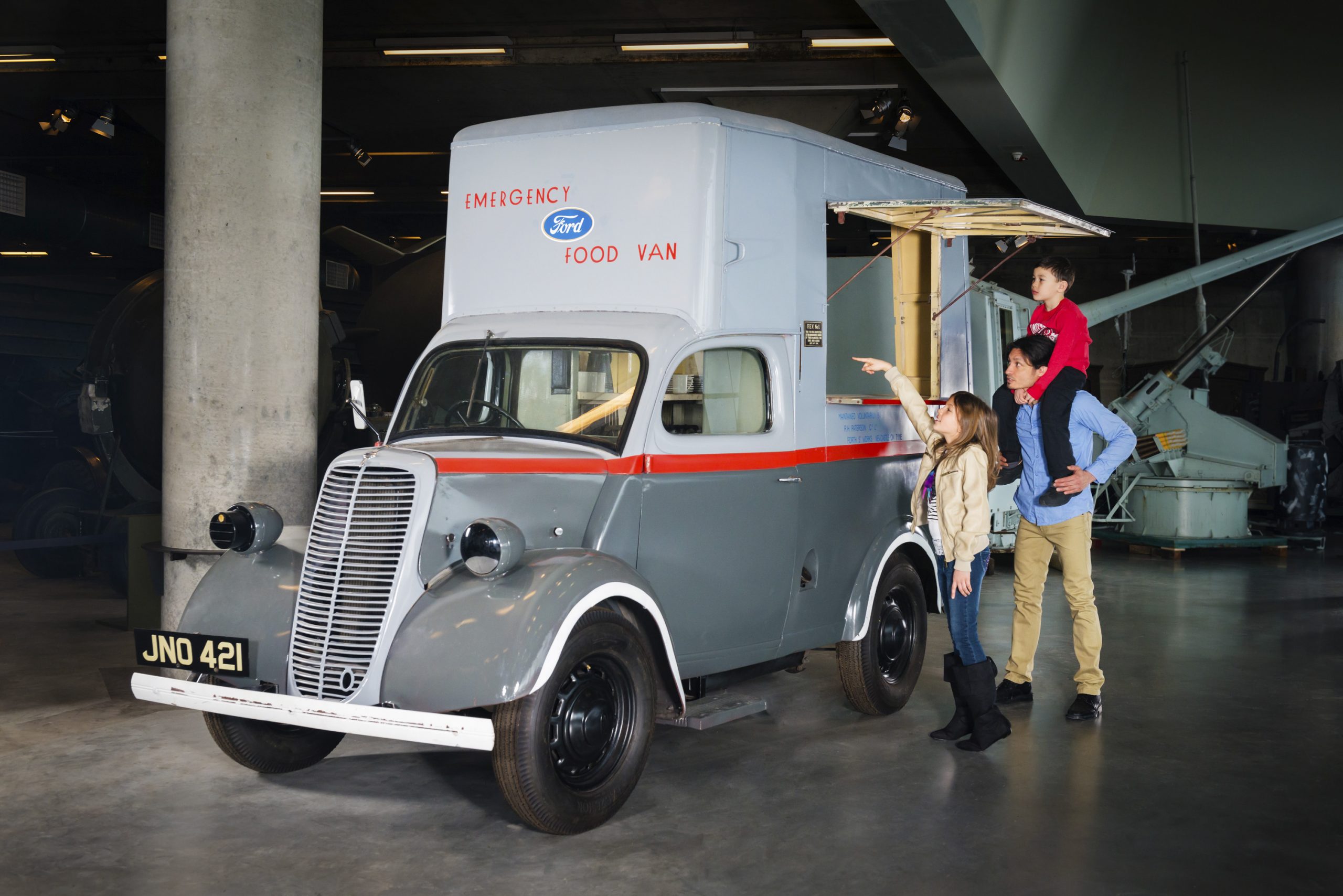 Une famille se tient à côté d’un camion d’époque dans un musée.