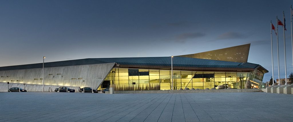 Un bâtiment moderne la nuit avec des drapeaux et des drapeaux.