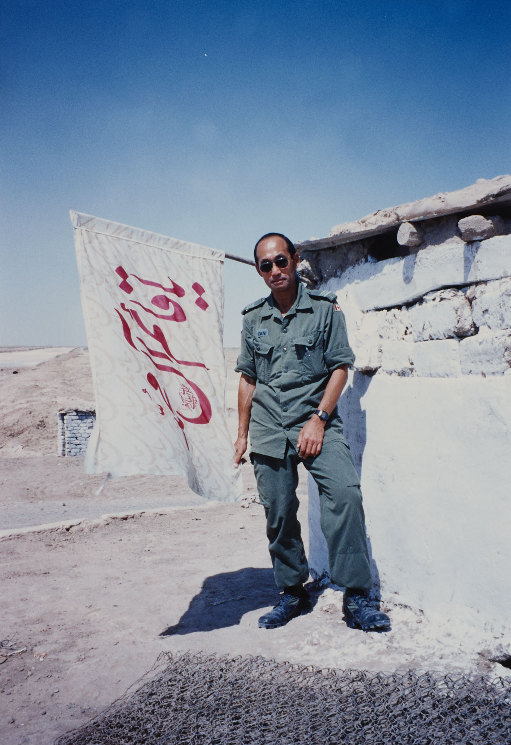 Ted Itani porte un uniforme et des lunettes de soleil.